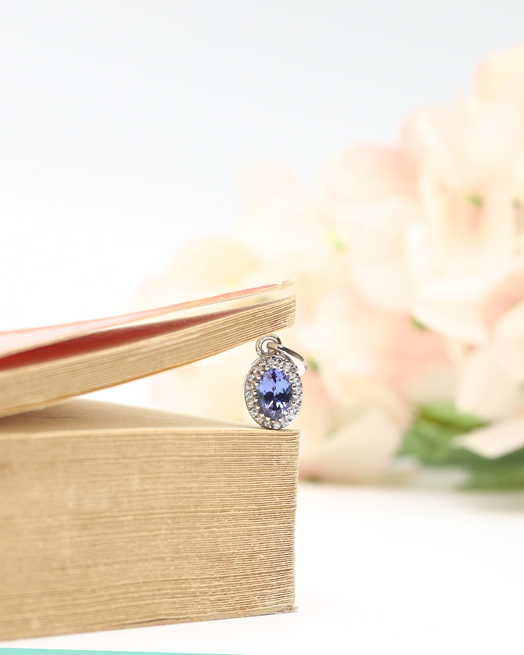 Timeless floral pendant with a oval-cut gemstone in a prong setting.