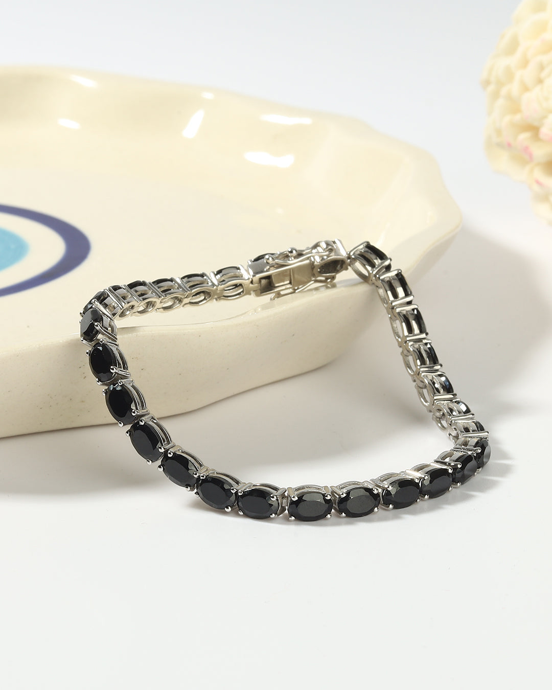 Elegant tennis bracelet with oval-cut gemstones in fine metal.