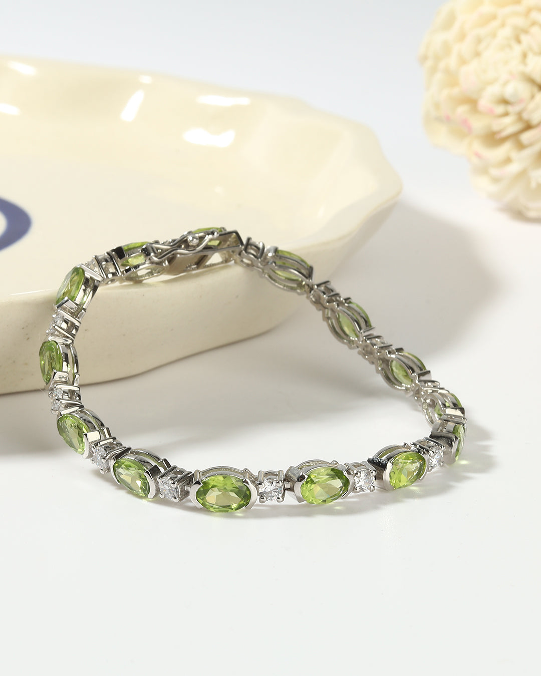 Elegant tennis bracelet with oval-cut gemstones in fine metal.