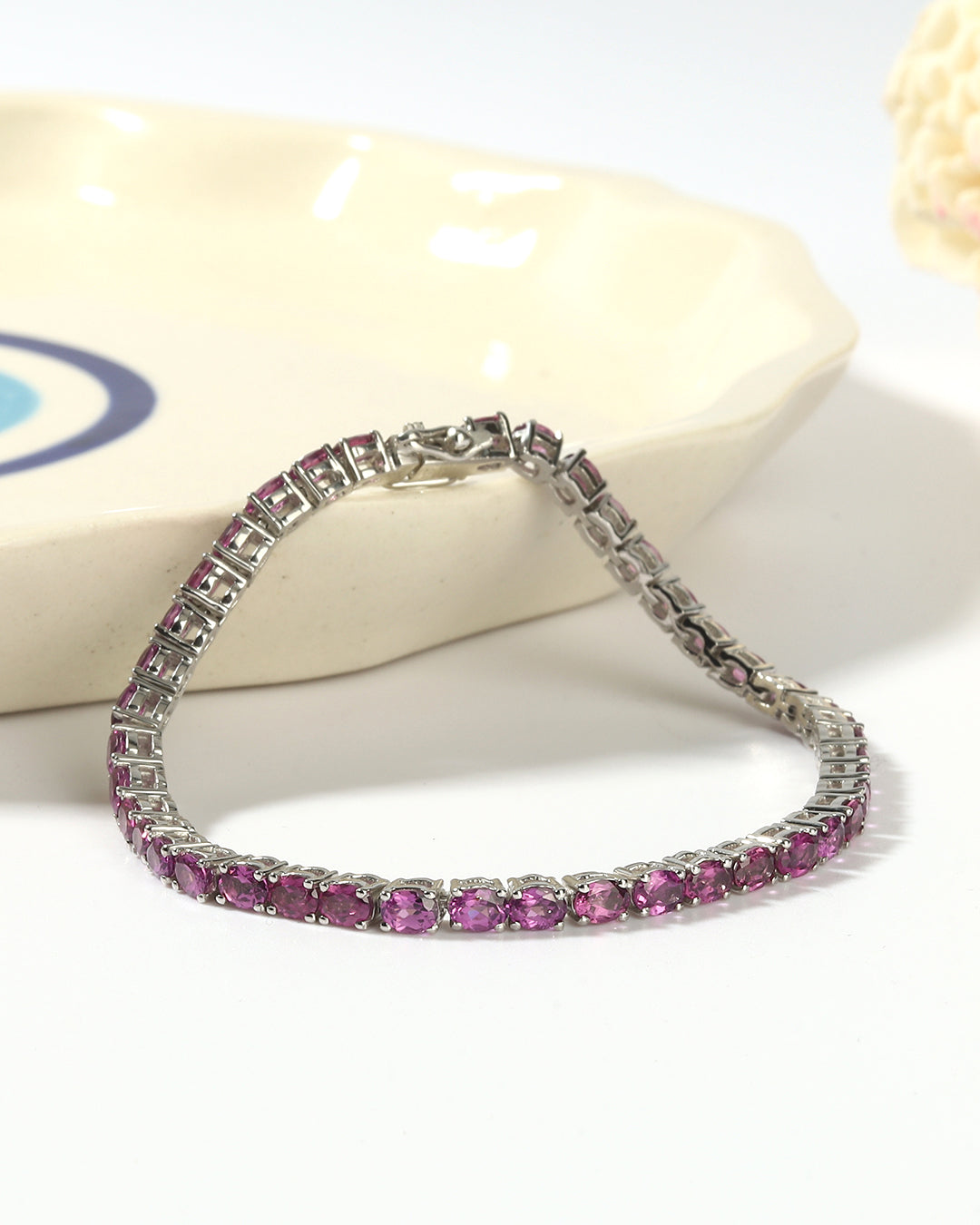 Elegant tennis bracelet with oval-cut gemstones in fine metal.