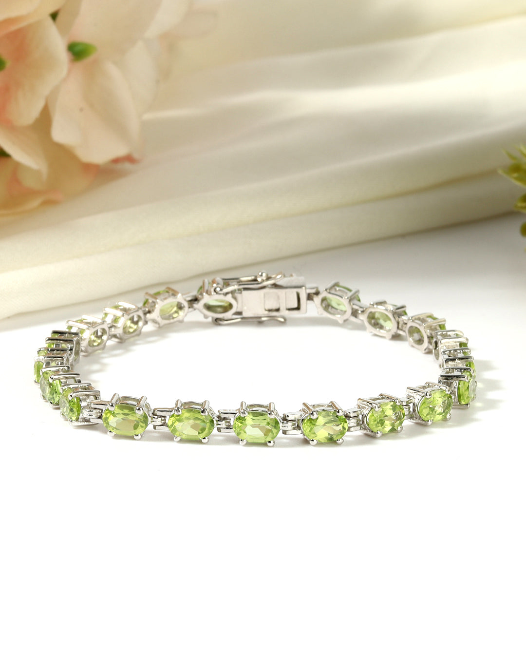 Elegant tennis bracelet with oval-cut gemstones in fine metal.